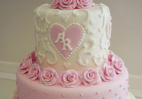 A traditional 3-tier Wedding Cake with pink flowers and white icing